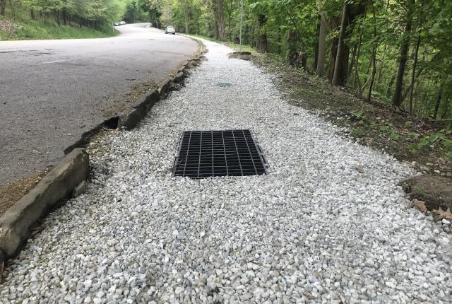 A gravel channel with a storm drain next to Overlook Drive in Schenley Park