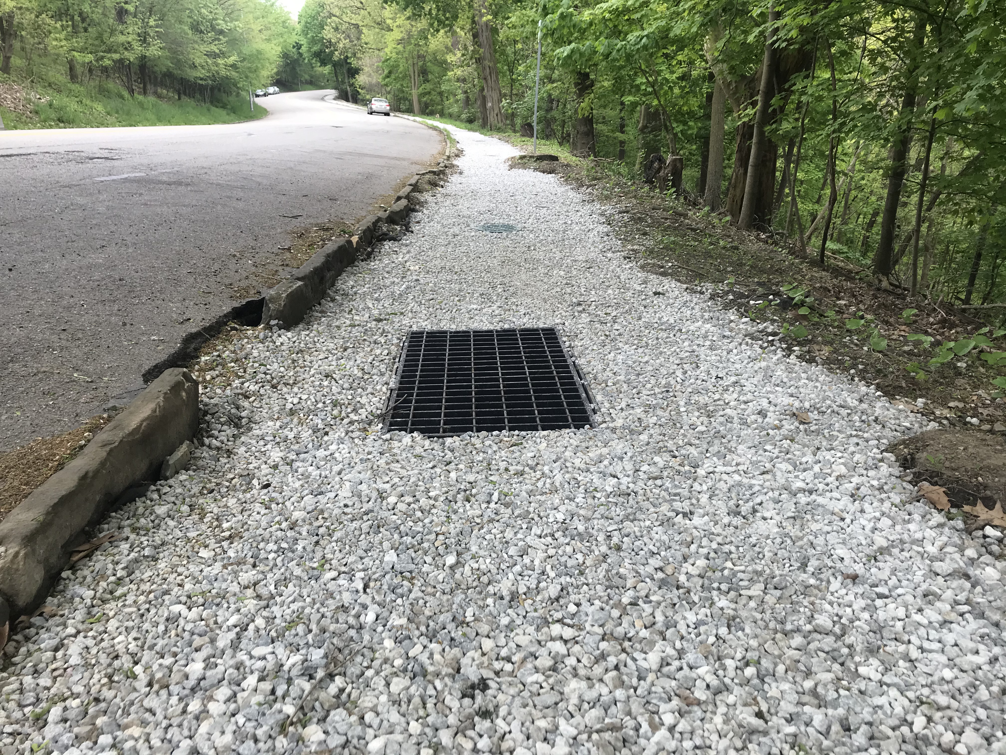 A gravel channel with a storm drain next to Overlook Drive in Schenley Park