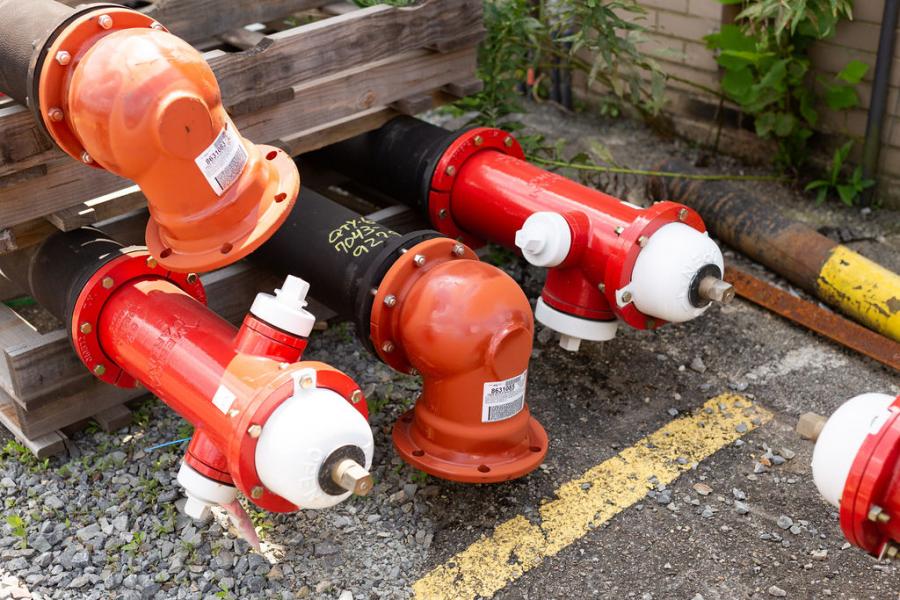 Fire hydrants and pipe extensions piled in a storage yard before going into the ground.
