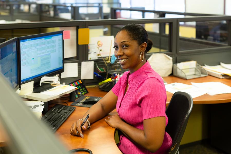 Customer Service Representative Natasha Butler smiles while sitting at her desk