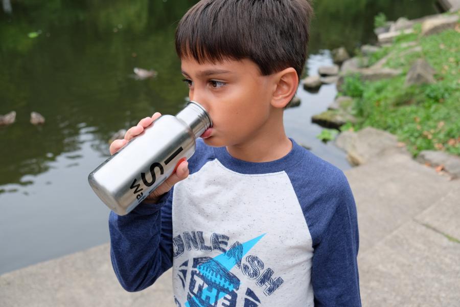A child drinking a reusable water bottle