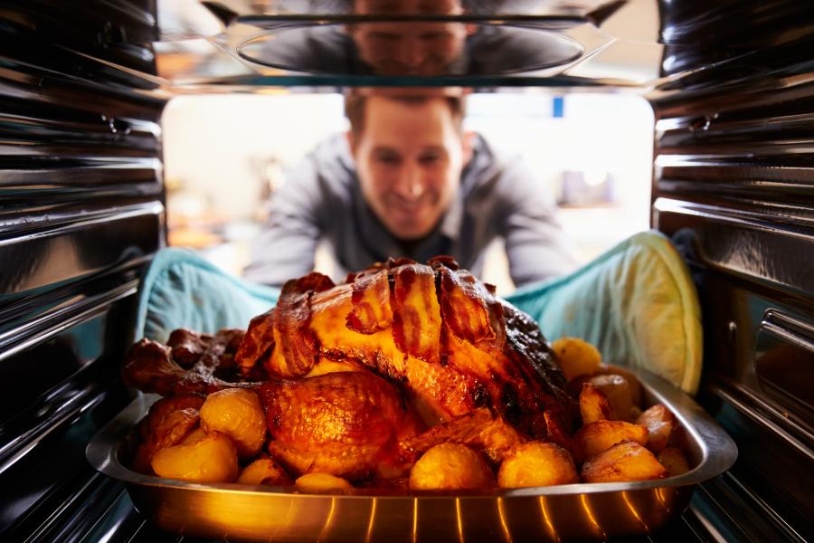 Man taking a roasted turkey out of the oven