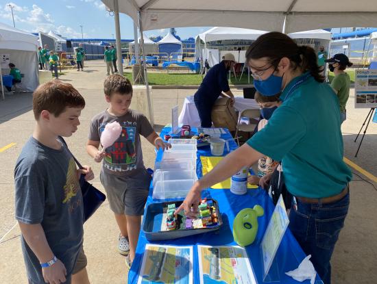 Photo of an adult showing two children a stormwater experiment activity