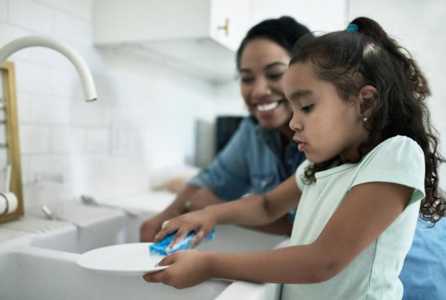 Stock photo of mother daughter at kitchen sink washing dishes