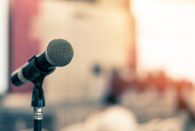 Stock photo of microphone staged for public to address a panel