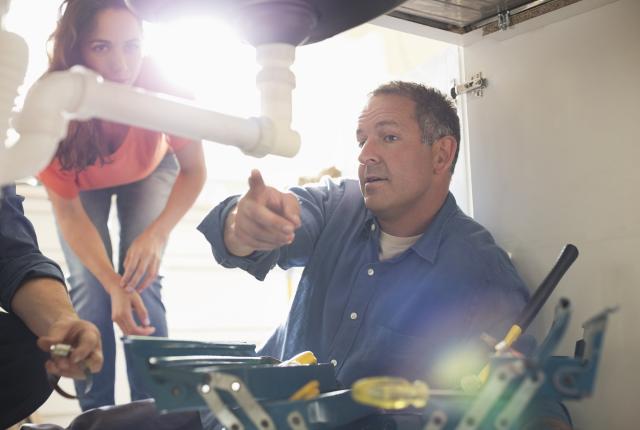 Stock photo of plumber pointing out a water leak to a customer