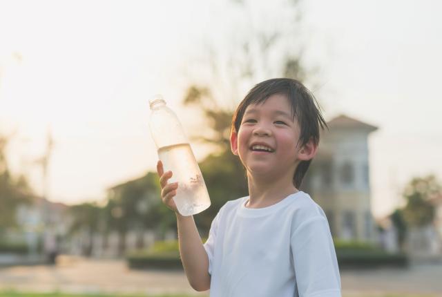 Stock photo of boy drinking water with happy expression